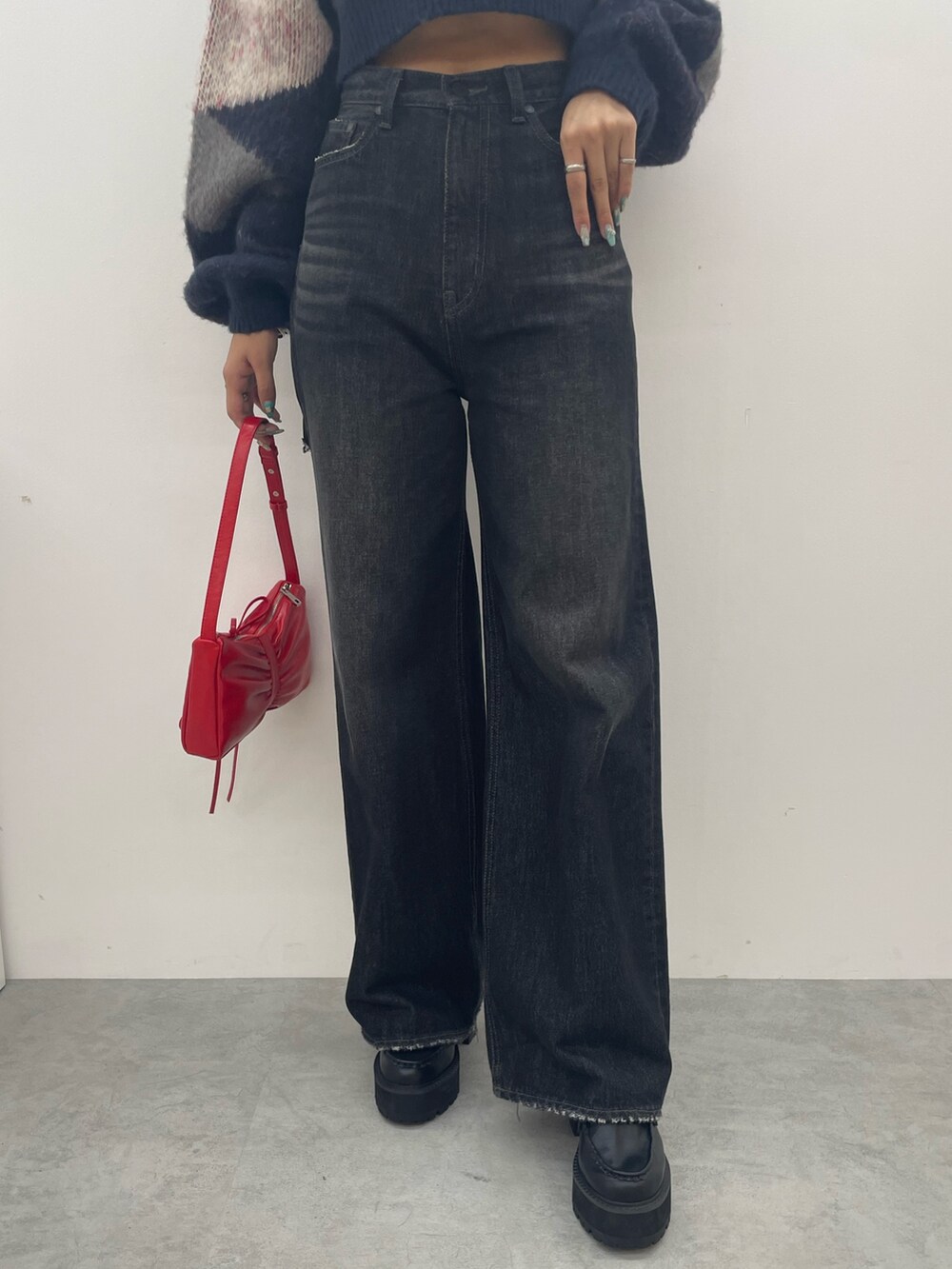 ブラック系のワンピース、ブラック系のデニムパンツ、ブラック系のブーツを着用したレディースの秋コーディネートの6枚目の写真