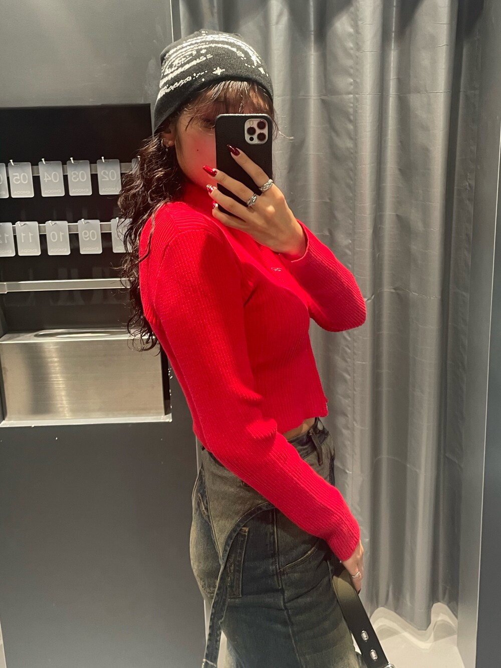 レッド系のニット/セーター、ブルー系のデニムパンツ、ブラック系のハンドバッグを着用したレディースの秋コーディネートの5枚目の写真