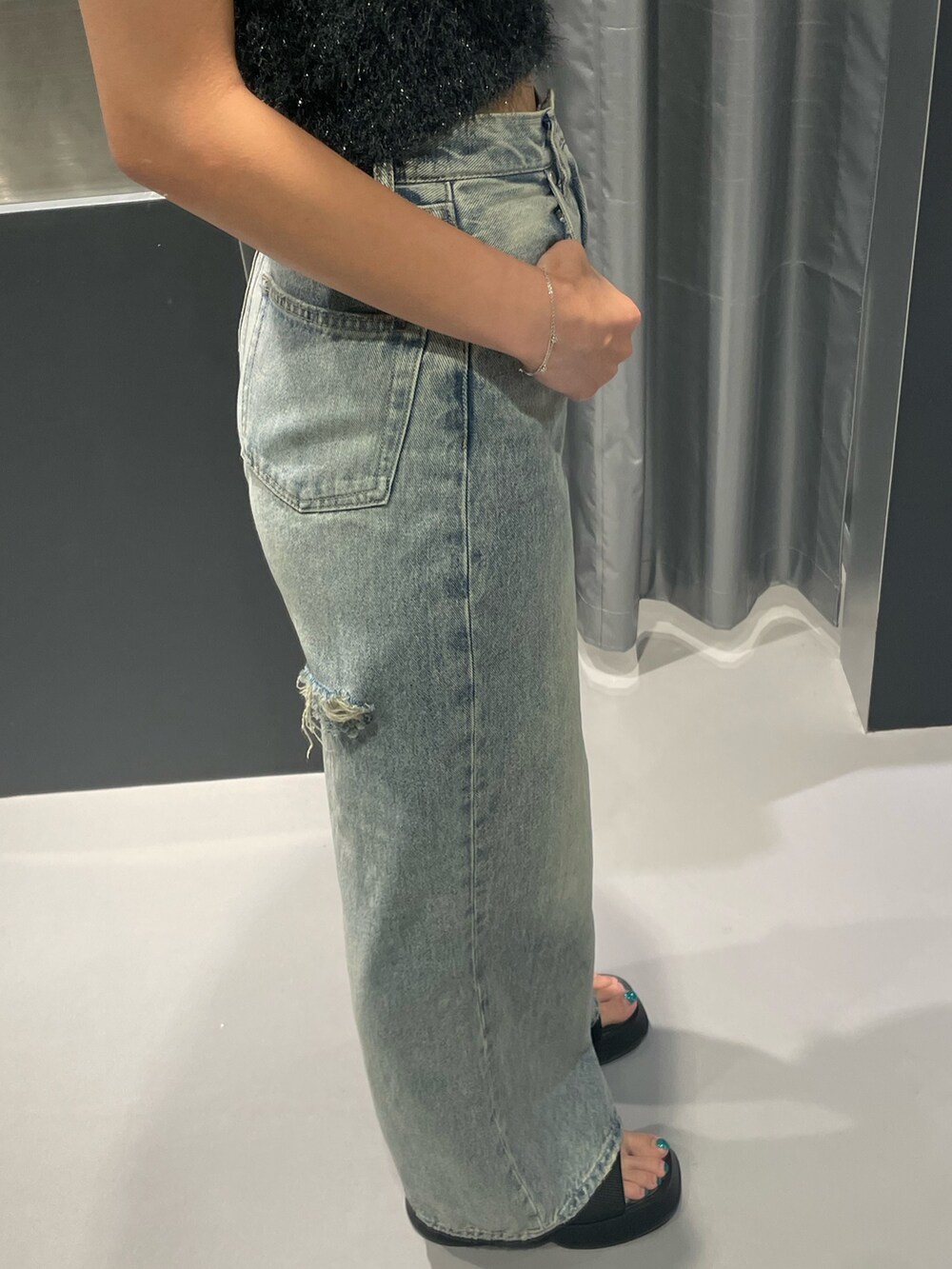 グレー系のタンクトップ、ブルー系のデニムパンツ、ブラック系のサンダルを着用したレディースの夏コーディネートの7枚目の写真