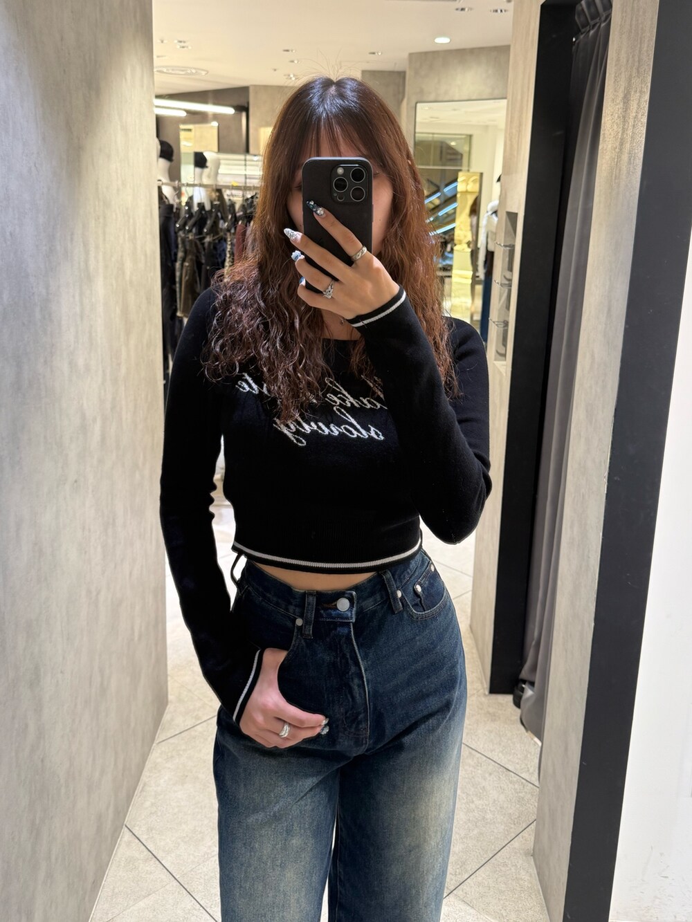 ブラック系のブーツ、ブラック系のニット/セーター、ブルー系のデニムパンツを着用したレディースの秋コーディネートの4枚目の写真