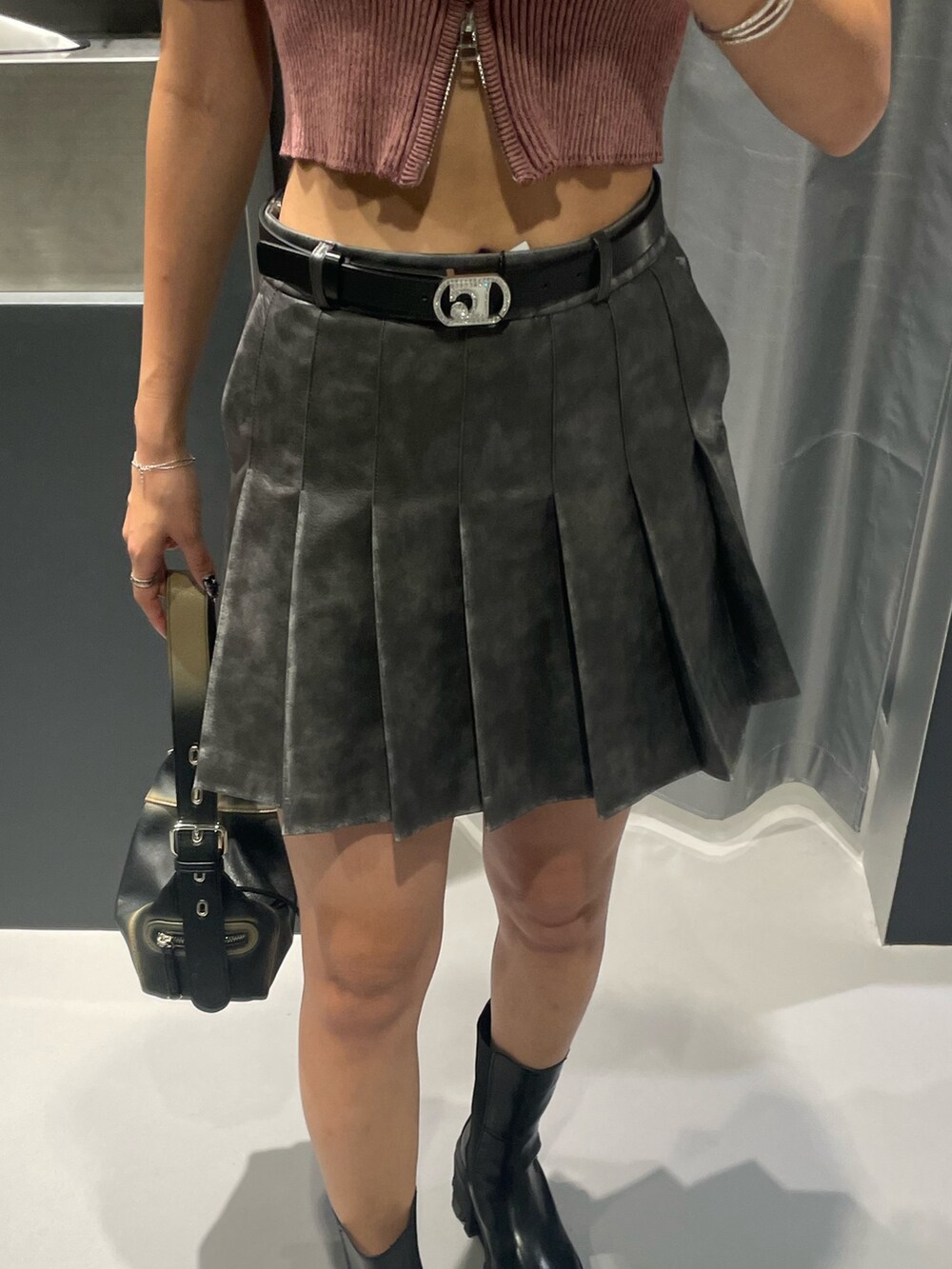 ピンク系のニット/セーター、グレー系のスカート、ブラック系のハンドバッグを着用したレディースの夏コーディネートの6枚目の写真