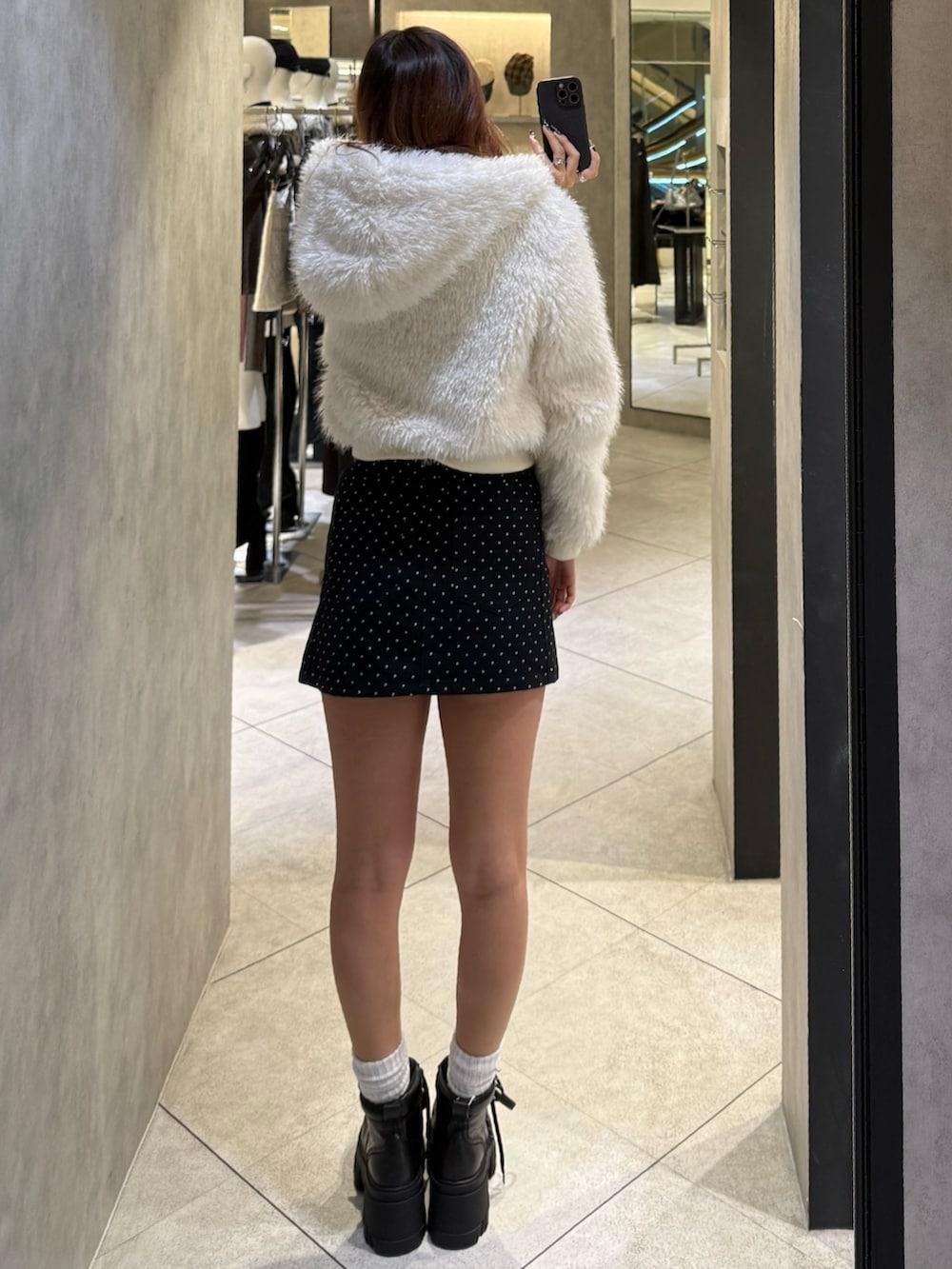 ホワイト系のブルゾン、ブラック系のニット/セーター、ブルー系のスカートを着用したレディースの秋コーディネートの3枚目の写真