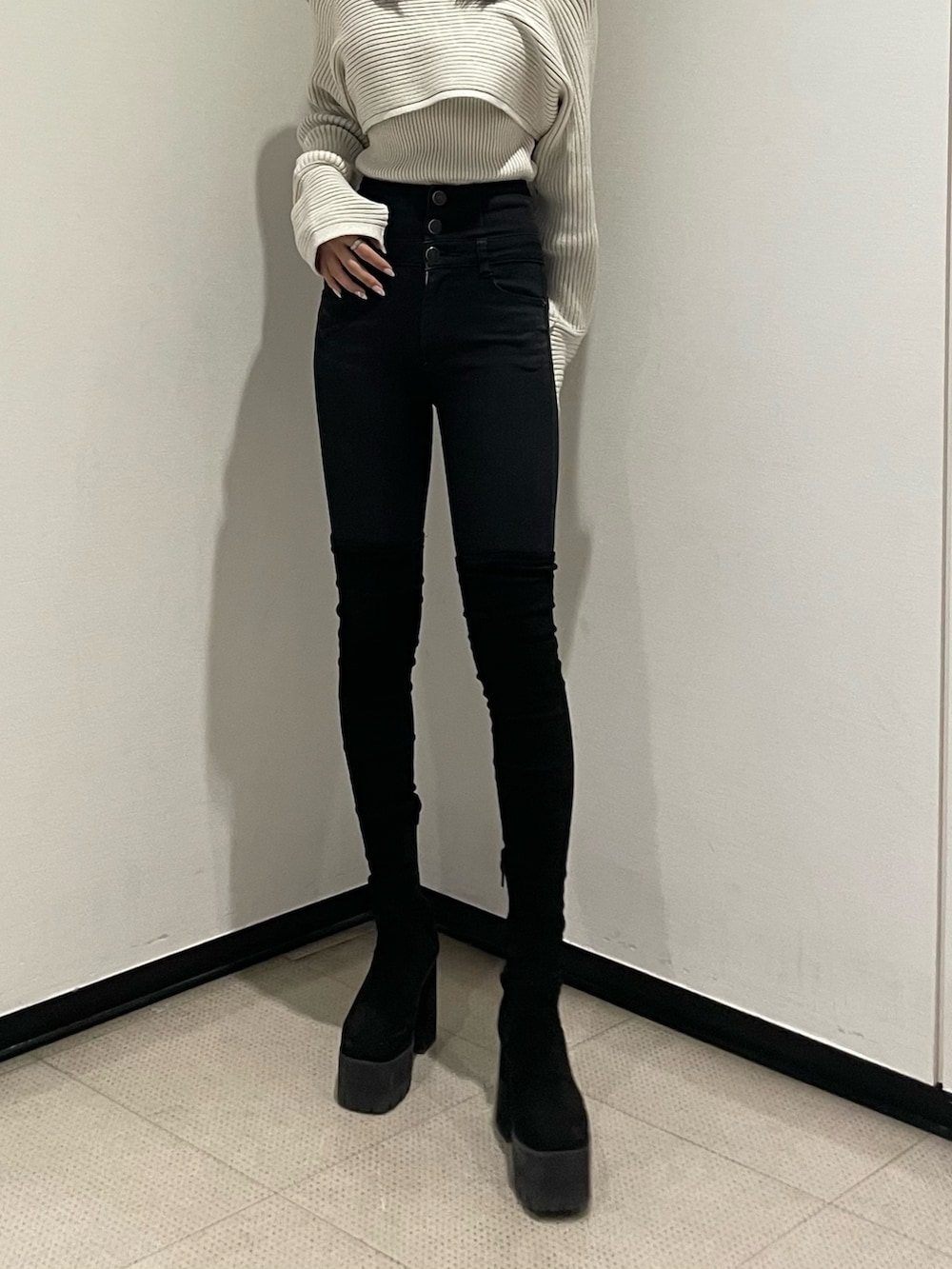 ホワイト系のニット/セーター、ブラック系のデニムパンツ、ブラック系のブーツを着用したレディースの秋コーディネートの7枚目の写真