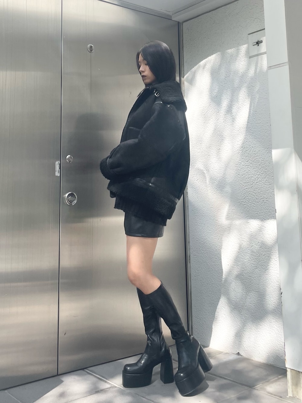 オレンジ系のニット/セーター、ブラック系のムートンコート、ブラック系のその他パンツを着用したレディースの秋コーディネートの2枚目の写真