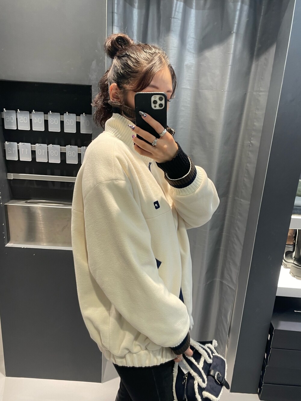 ホワイト系のブルゾン、ブルー系のハンドバッグ、ブラック系のデニムパンツを着用したレディースの秋コーディネートの5枚目の写真