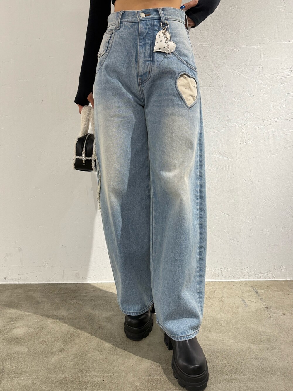 ホワイト系のニット/セーター、ブルー系のデニムパンツ、ブラック系のハンドバッグを着用したレディースの秋コーディネートの5枚目の写真