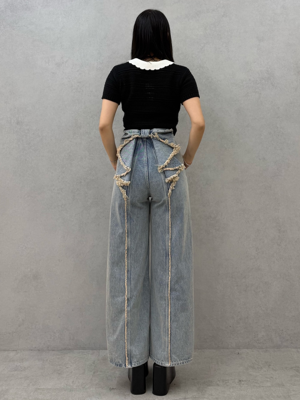 ブラック系のニット/セーター、ブルー系のデニムパンツ、ブラック系のサンダルを着用したレディースの春コーディネートの3枚目の写真