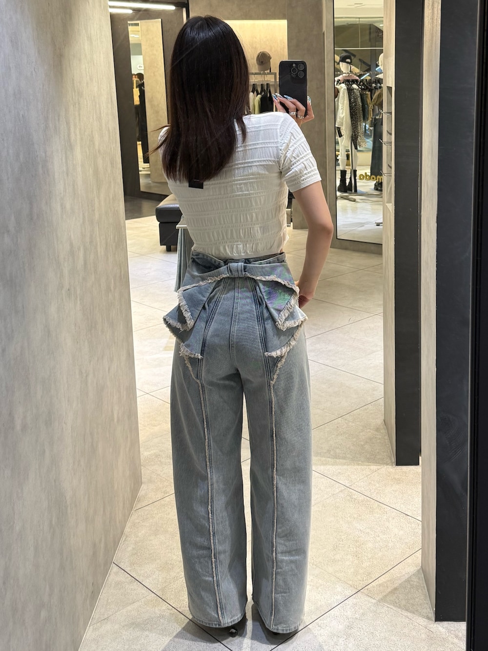 ホワイト系のニット/セーター、ブルー系のデニムパンツ、ブラック系のスニーカーを着用したレディースの春コーディネートの3枚目の写真