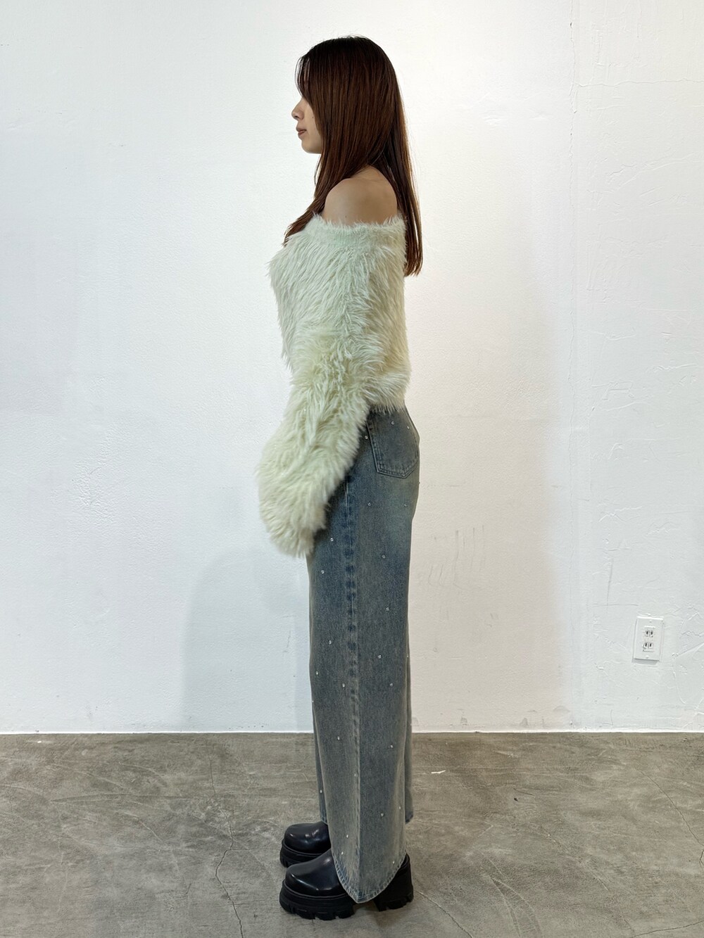 ホワイト系のニット/セーター、ブルー系のデニムパンツ、ブラック系のブーツを着用したレディースの冬コーディネートの2枚目の写真