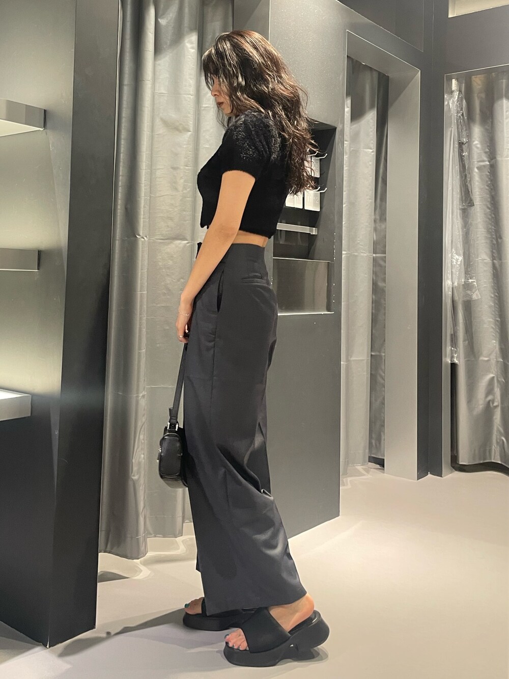 ブラック系のニット/セーター、グレー系のその他パンツ、ブラック系のショルダーバッグを着用したレディースの夏コーディネートの2枚目の写真