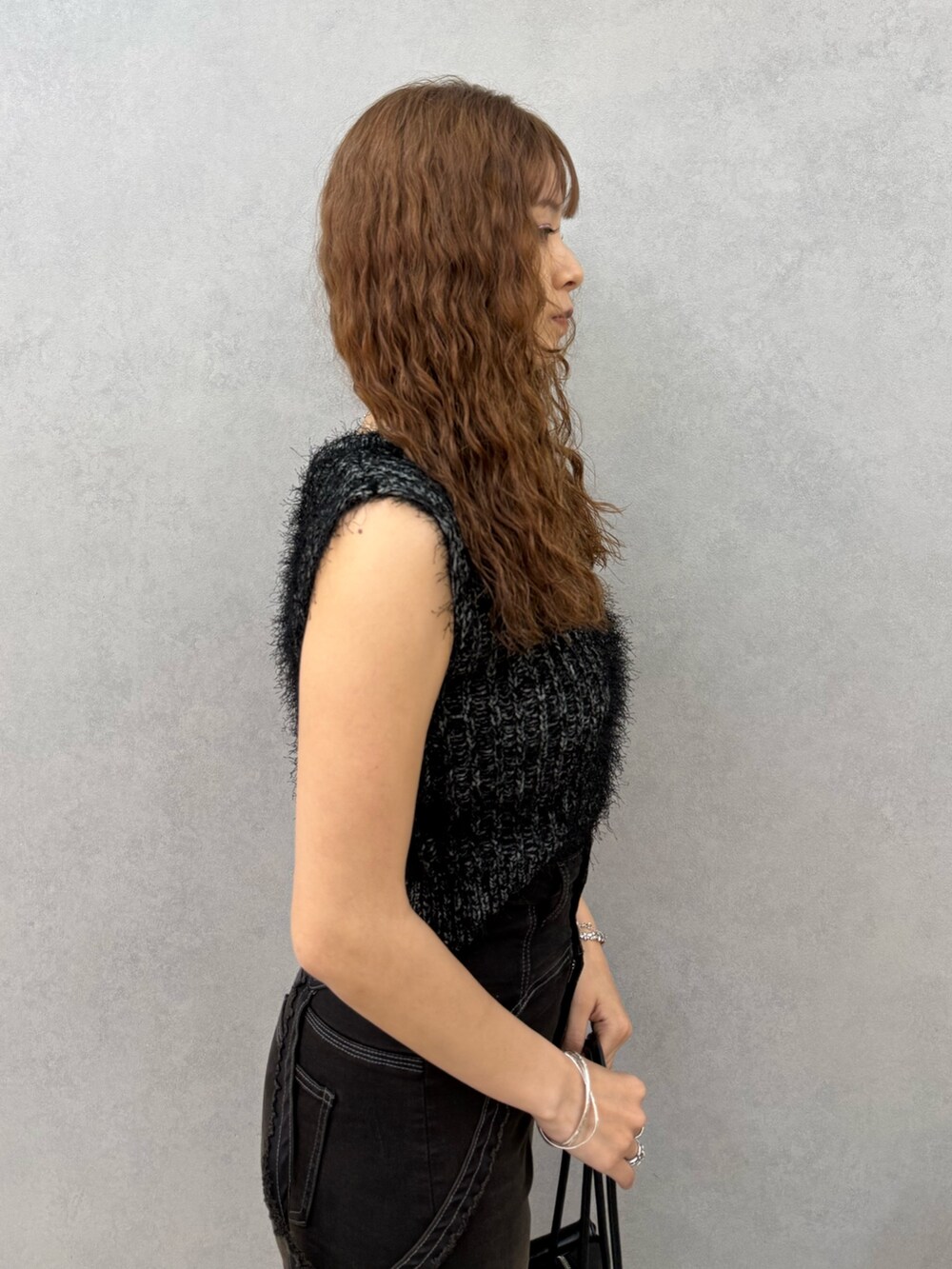 ブラック系のニット/セーター、ブラック系のデニムパンツ、ブラック系のハンドバッグを着用したレディースの夏コーディネートの5枚目の写真