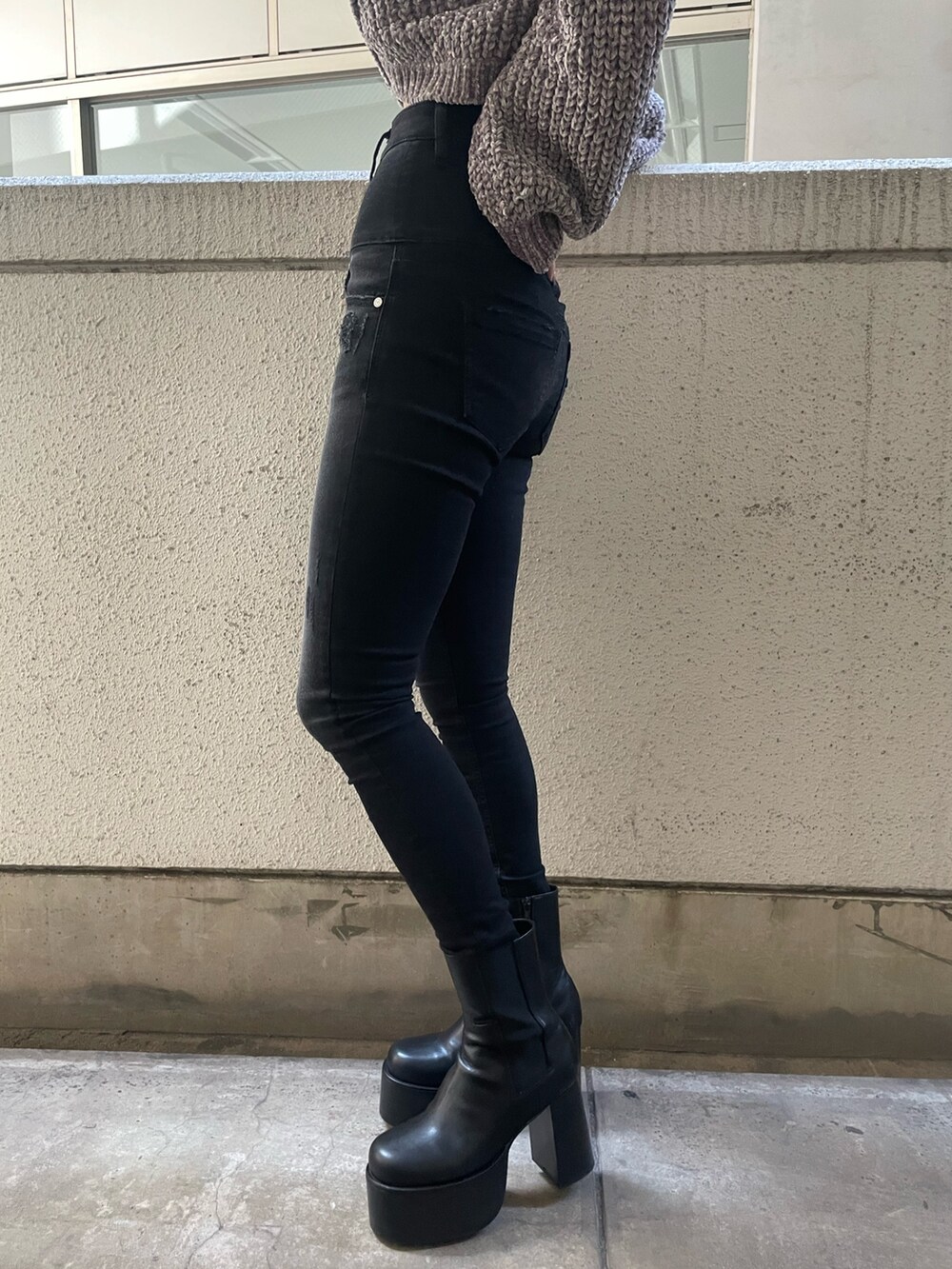 グレー系のニット/セーター、ブラック系のハンドバッグ、ブラック系のデニムパンツを着用したレディースの冬コーディネートの8枚目の写真