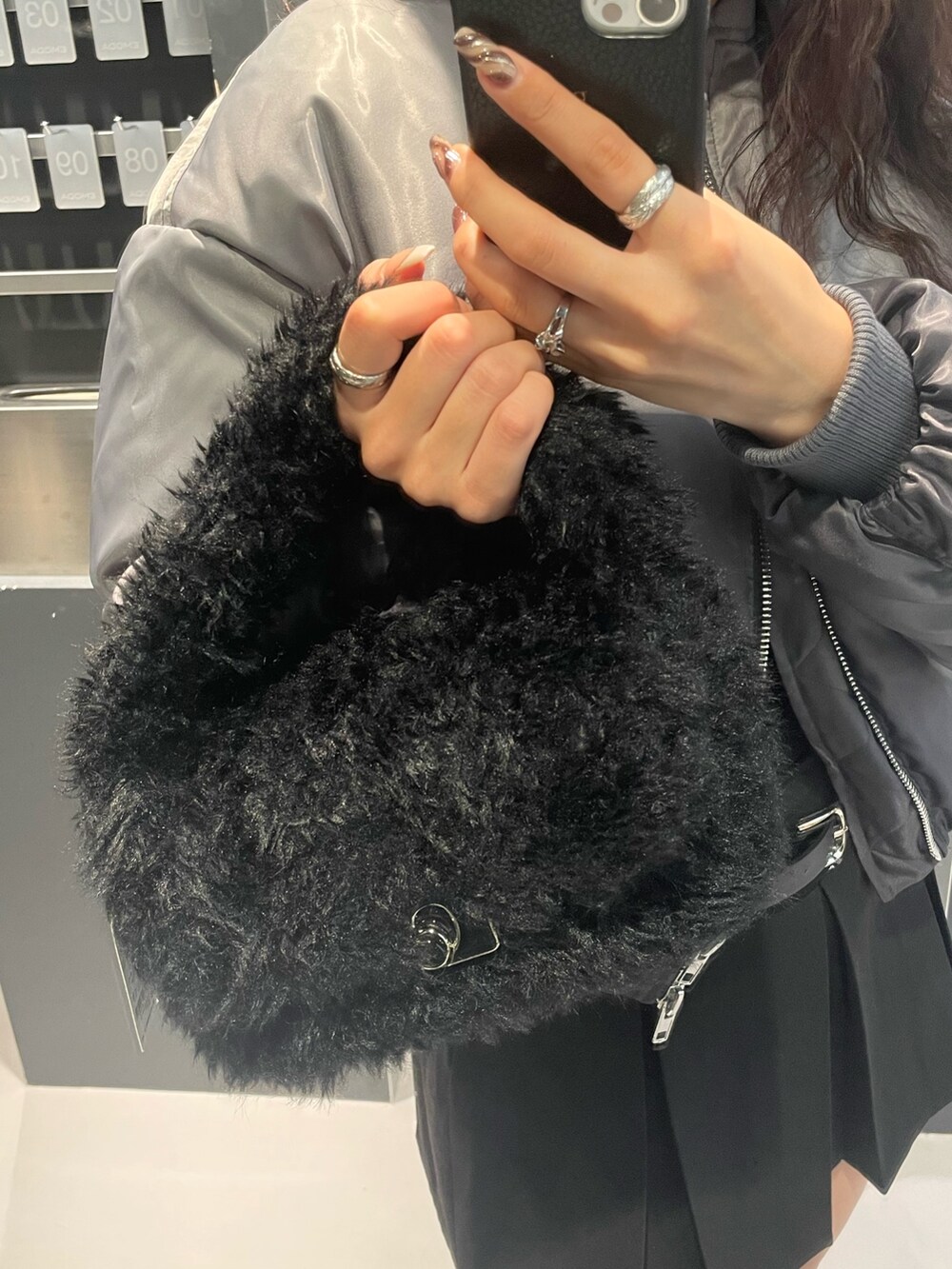 グレー系のニット/セーター、ブラック系のスカート、ブラック系のハンドバッグを着用したレディースの冬コーディネートの8枚目の写真