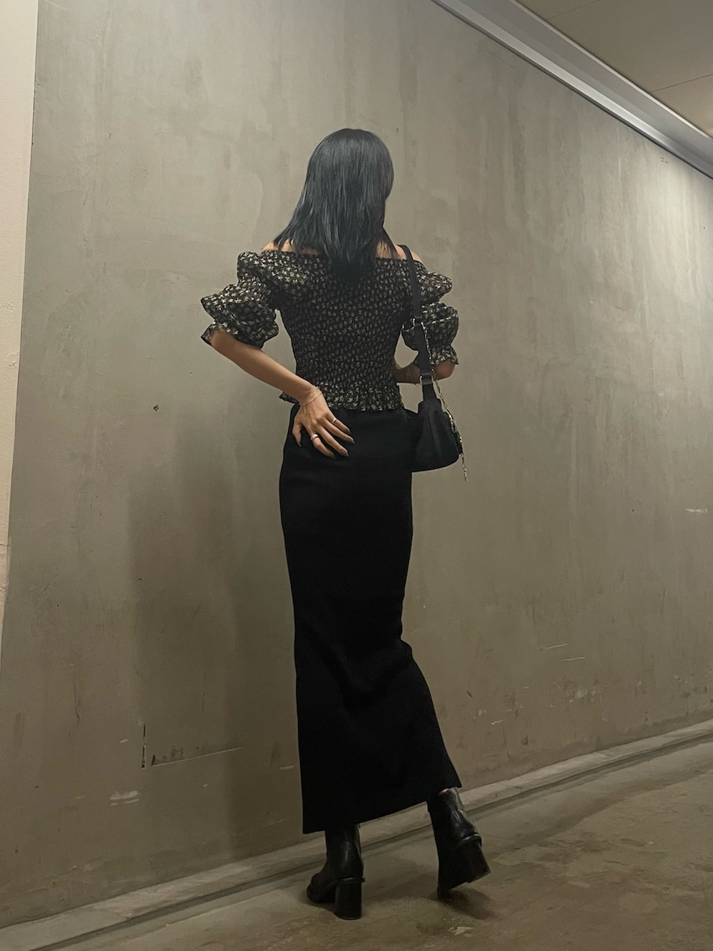 ブラック系のハンドバッグ、ブラック系のスカート、ブラック系のブーツを着用したレディースの秋コーディネートの7枚目の写真