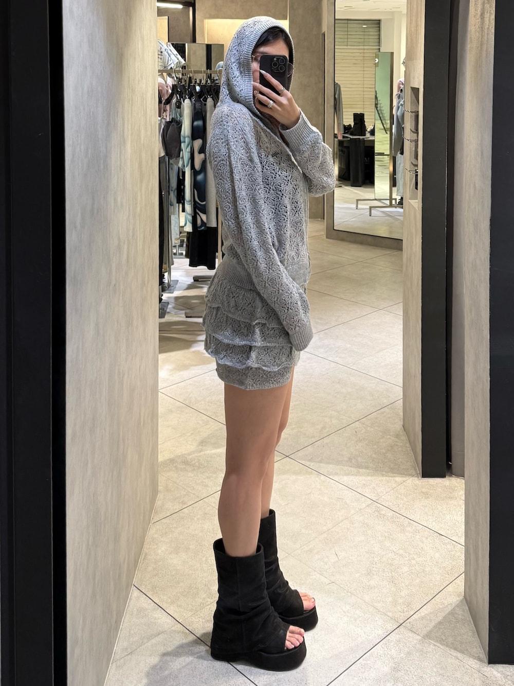 グレー系のパーカー、グレー系のスカート、ブラック系のサンダルを着用したレディースの春コーディネートの2枚目の写真