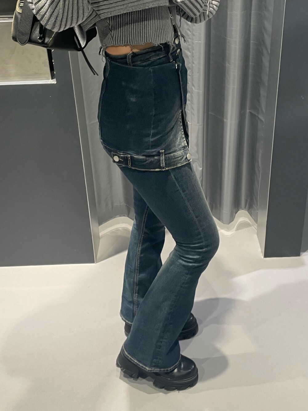 グレー系のニット/セーター、ブルー系のデニムパンツ、ブラック系のハンドバッグを着用したレディースの秋コーディネートの7枚目の写真