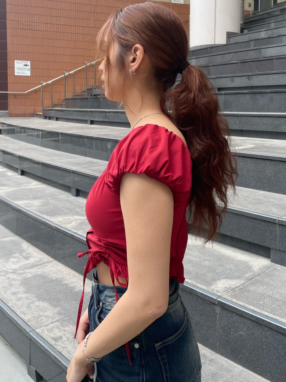 レッド系のTシャツ/カットソー、ブルー系のデニムパンツ、ブラック系のハンドバッグを着用したレディースの春コーディネートの5枚目の写真