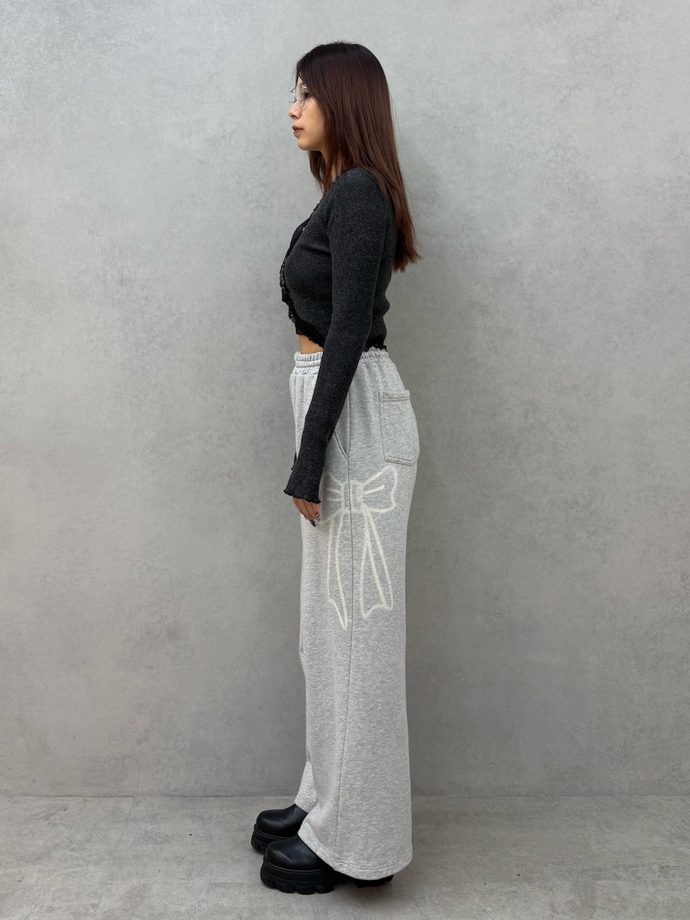 ブラック系のニット/セーター、グレー系のスウェットパンツ、ブラック系のブーツを着用したレディースの冬コーディネートの2枚目の写真