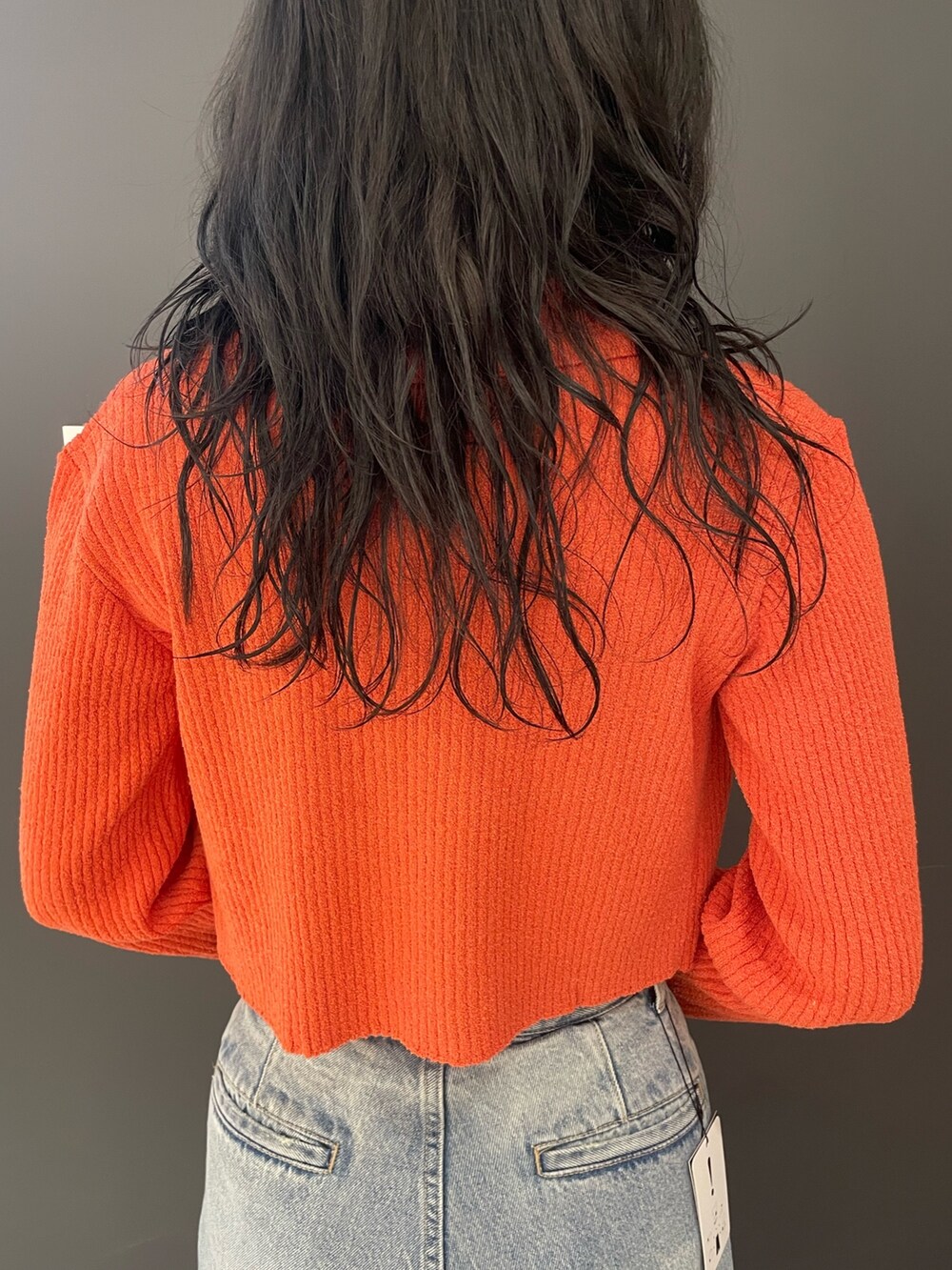 オレンジ系のニット/セーター、ブルー系のデニムパンツ、ブラック系のパンプスを着用したレディースの春コーディネートの6枚目の写真