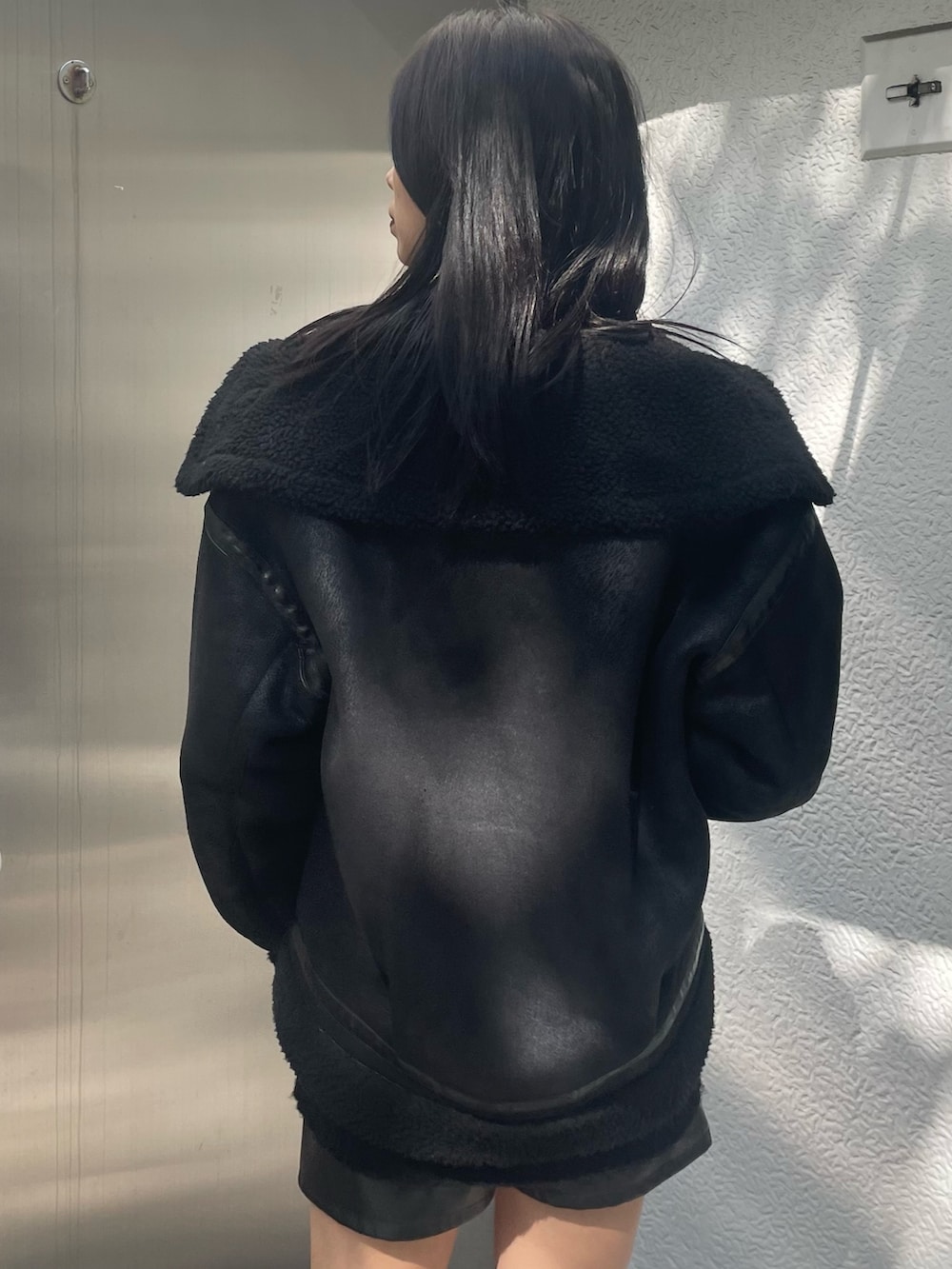 オレンジ系のニット/セーター、ブラック系のムートンコート、ブラック系のその他パンツを着用したレディースの秋コーディネートの5枚目の写真