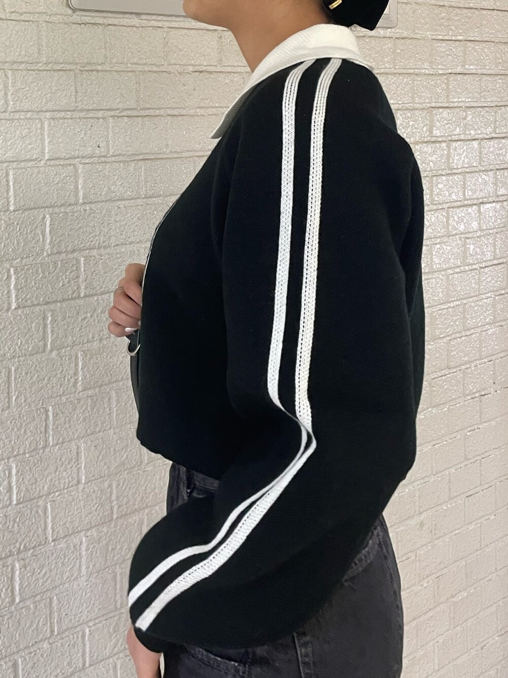 ブラック系のニット/セーター、ブラック系のハンドバッグ、ブラック系のデニムパンツを着用したレディースの冬コーディネートの5枚目の写真