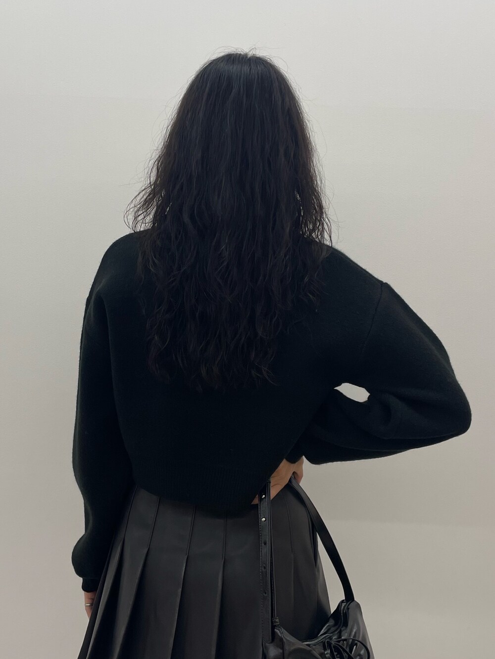 ブラック系のニット/セーター、ブルー系のデニムパンツ、ブラック系のショルダーバッグを着用したレディースの夏コーディネートの6枚目の写真