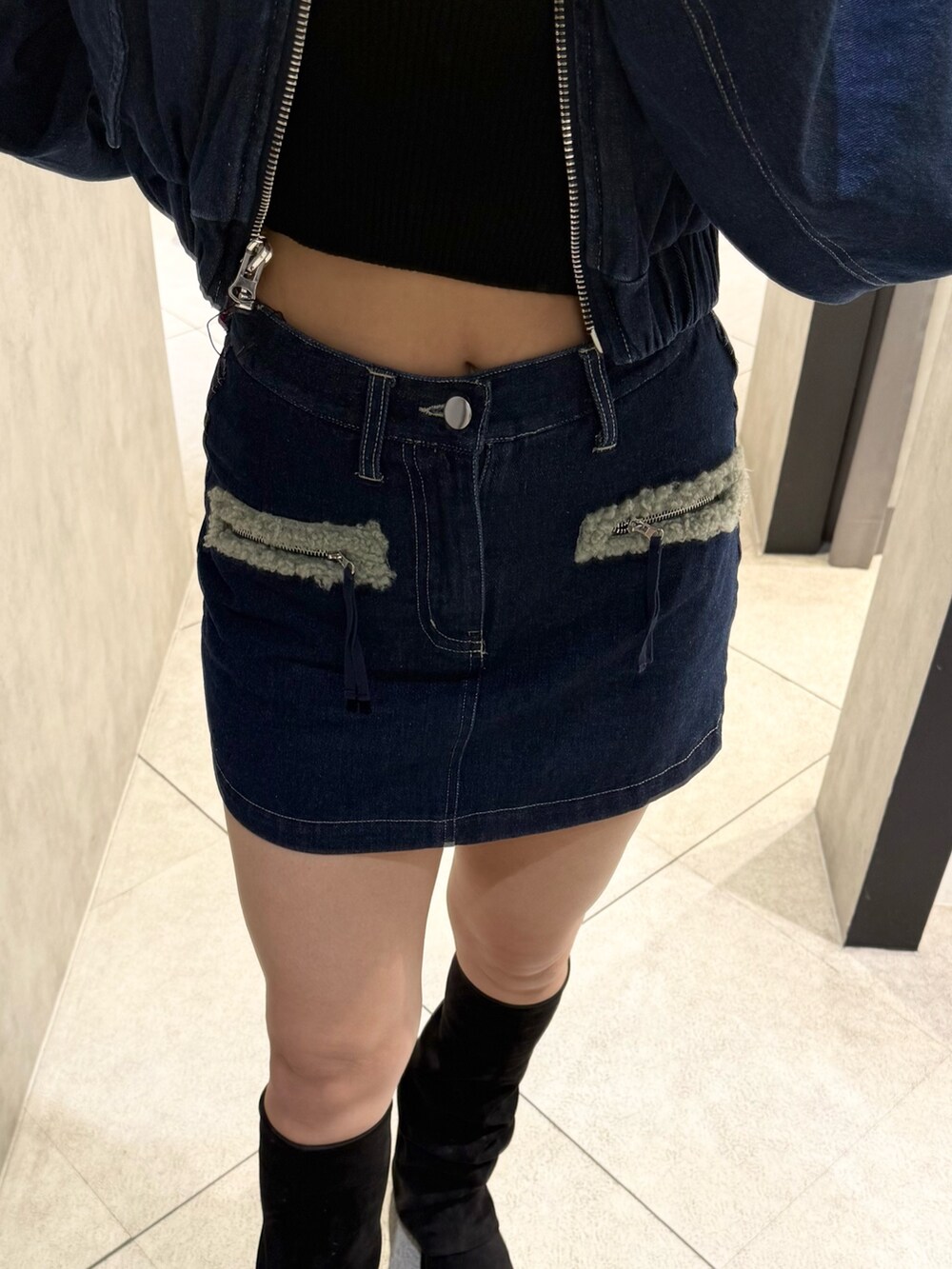 グレー系のニット/セーター、ブルー系のスカート、ブラック系のブーツを着用したレディースの秋コーディネートの5枚目の写真