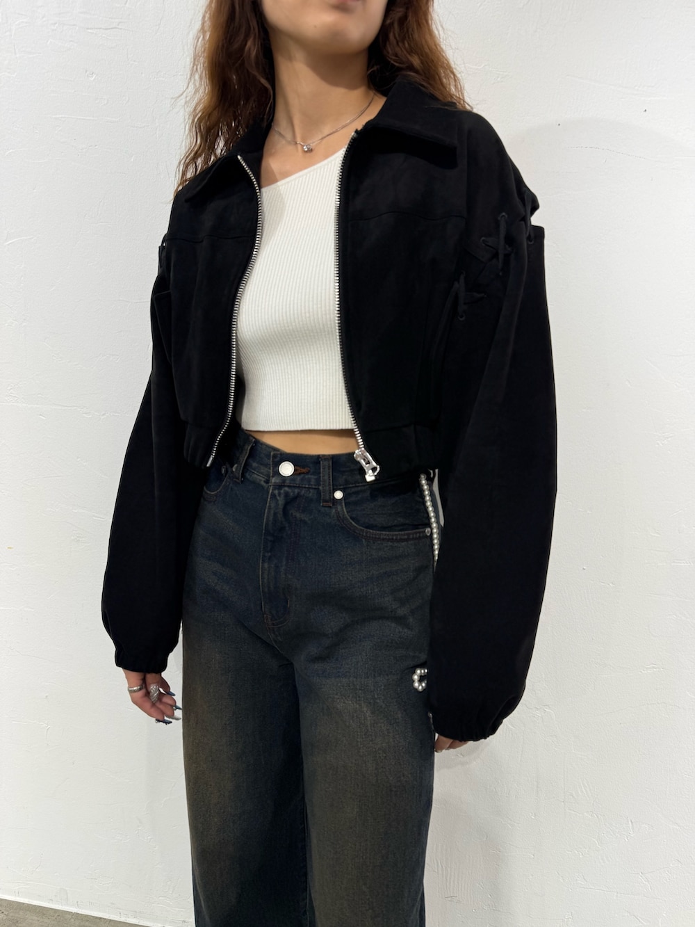 ホワイト系のニット/セーター、ブラック系のブルゾン、ブルー系のデニムパンツを着用したレディースの秋コーディネートの4枚目の写真