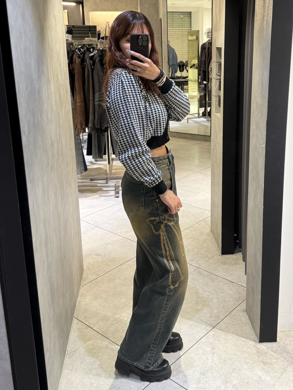 ブラック系のニット/セーター、ブルー系のデニムパンツ、ブラック系のブーツを着用したレディースの秋コーディネートの2枚目の写真