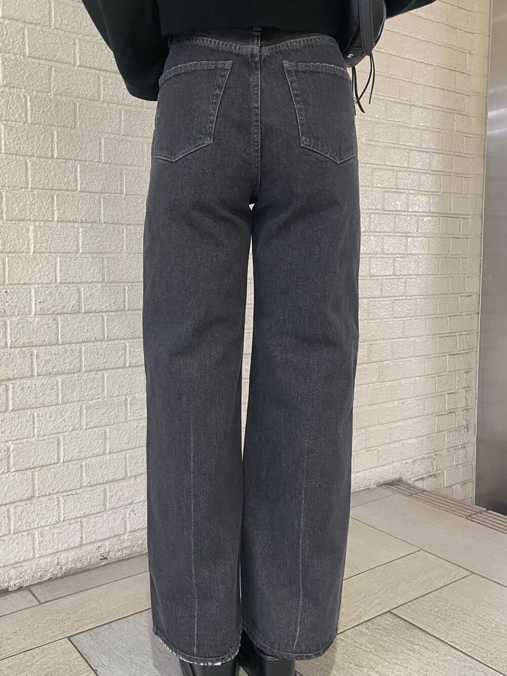 ブラック系のニット/セーター、ブラック系のハンドバッグ、ブラック系のデニムパンツを着用したレディースの冬コーディネートの8枚目の写真