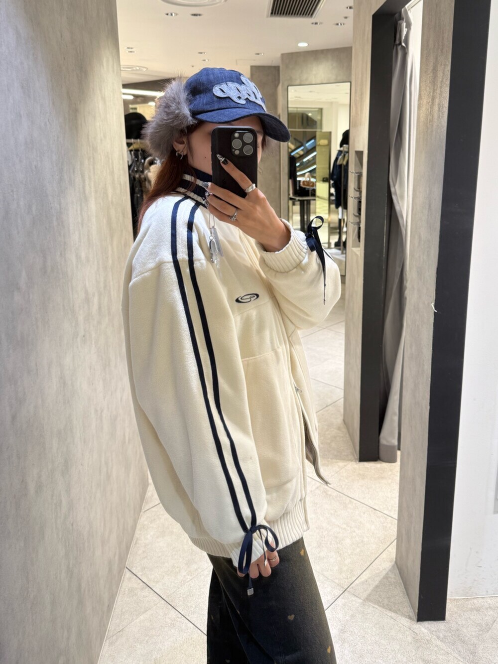 ブラック系のブーツ、ブルー系のデニムパンツ、ホワイト系のブルゾンを着用したレディースの秋コーディネートの5枚目の写真