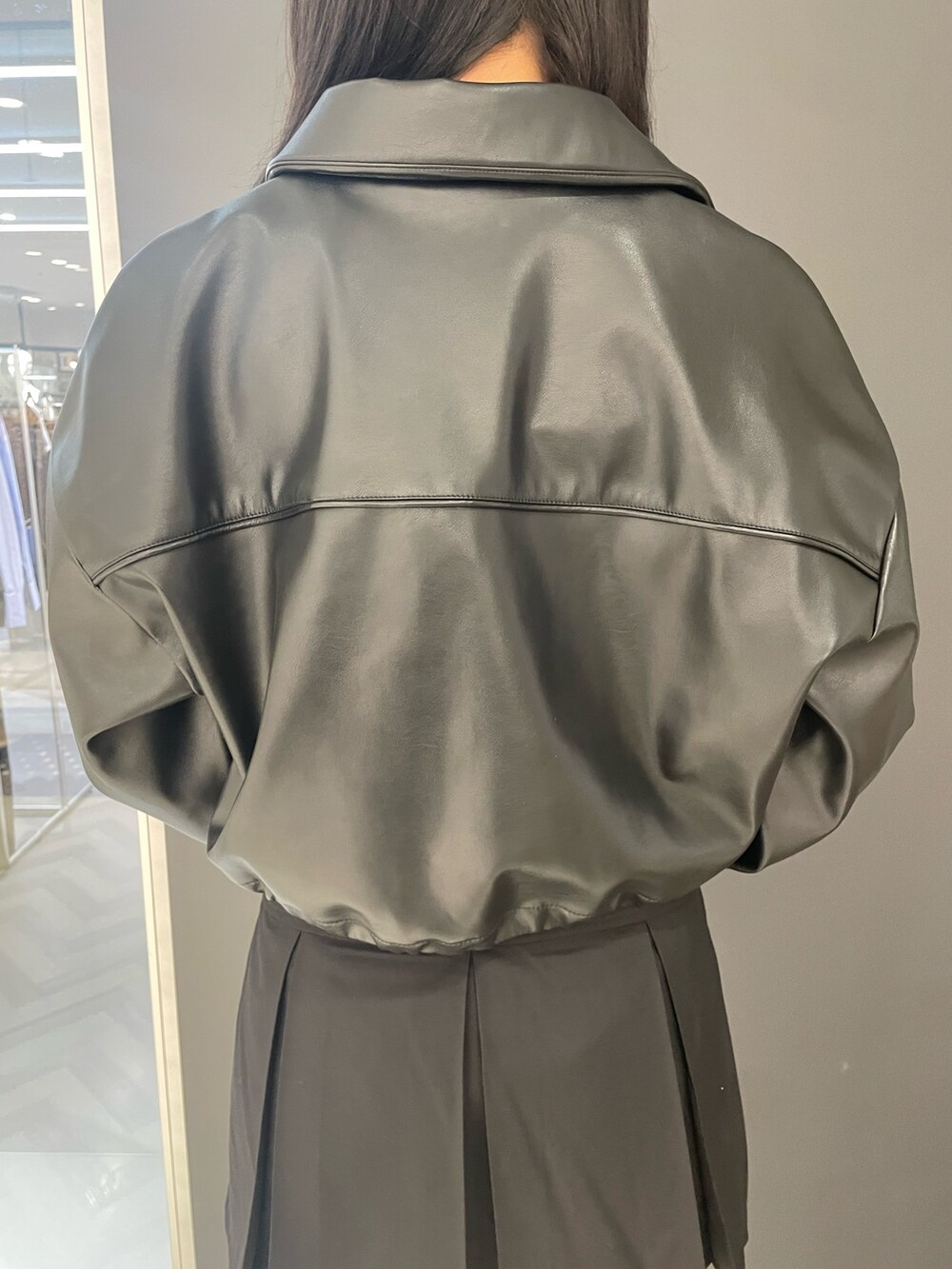 ホワイト系のタンクトップ、ブラック系のブルゾン、ブラック系のスカートを着用したレディースの春コーディネートの6枚目の写真