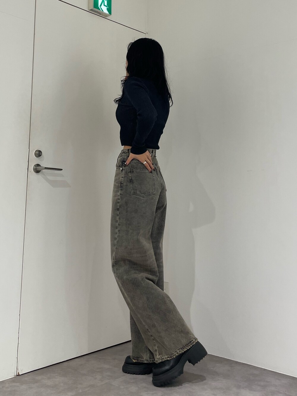 ブラック系のニット/セーター、グレー系のデニムパンツ、ブラック系のブーツを着用したレディースの春コーディネートの2枚目の写真