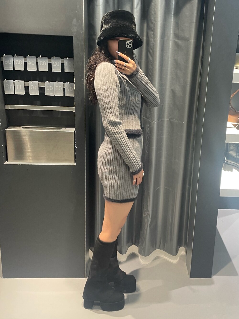 グレー系のニット/セーター、グレー系のスカート、ブラック系のブーツを着用したレディースの秋コーディネートの2枚目の写真