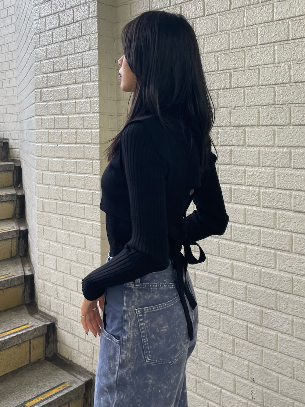 ブラック系のニット/セーター、パープル系のデニムパンツ、ブラック系のブーツを着用したレディースの秋コーディネートの6枚目の写真