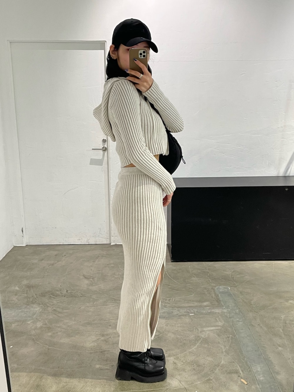 ホワイト系のワンピース、ブラック系のキャミソール、ブラック系のブーツを着用したレディースの春コーディネートの2枚目の写真