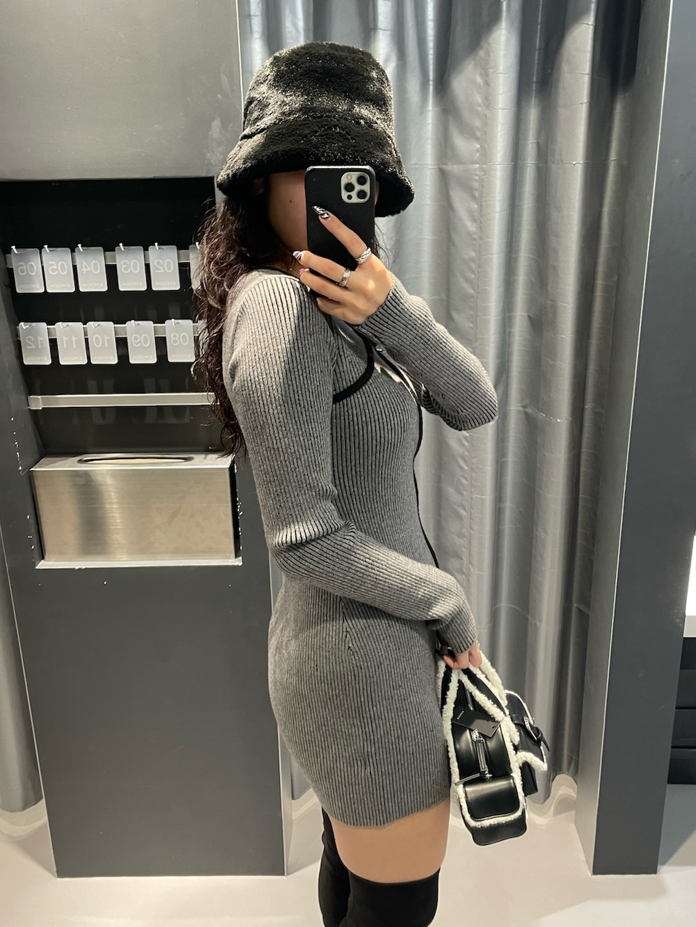 グレー系のワンピース、ブラック系のハンドバッグ、ブラック系のブーツを着用したレディースの冬コーディネートの5枚目の写真