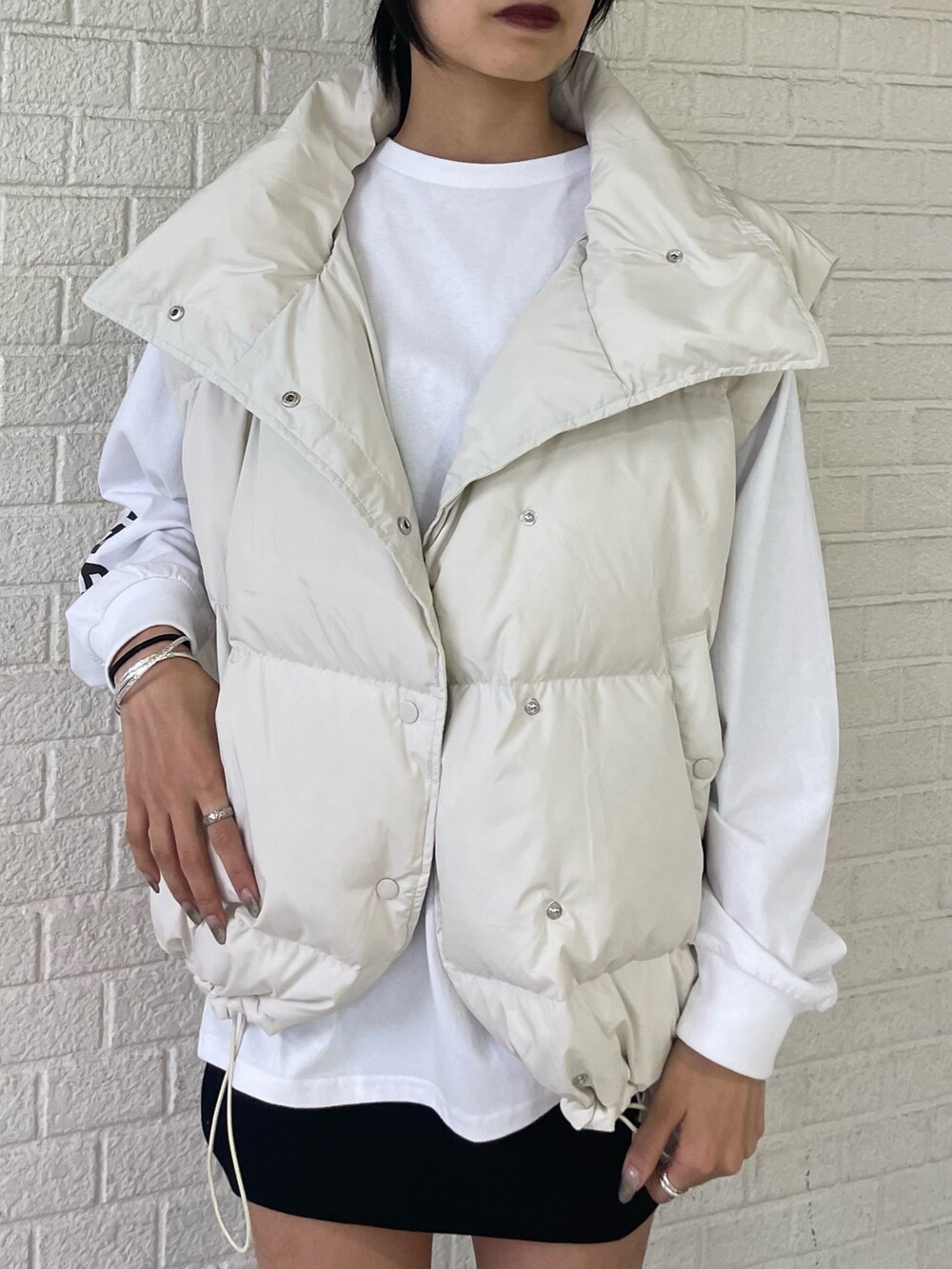 ホワイト系のTシャツ/カットソー、ホワイト系のダウンベスト、ブラック系のスカートを着用したレディースの秋コーディネートの4枚目の写真