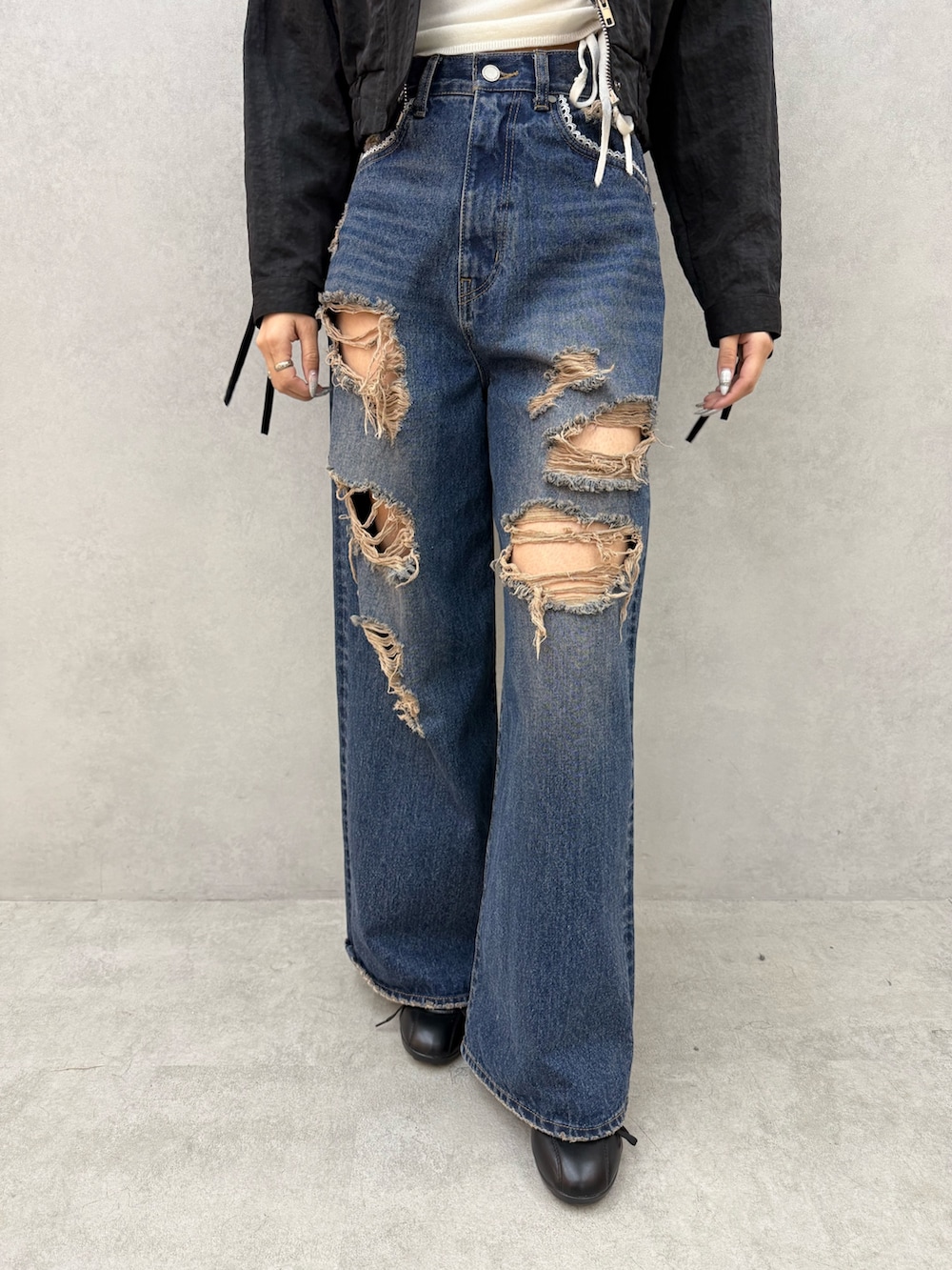 ブラック系のブルゾン、ホワイト系のニット/セーター、ブルー系のデニムパンツを着用したレディースの冬コーディネートの6枚目の写真