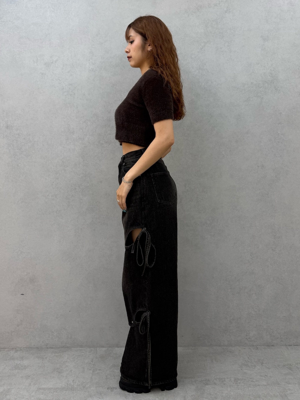 ブラウン系のニット/セーター、ブラック系のデニムパンツ、ブラウン系のブーツを着用したレディースの夏コーディネートの2枚目の写真