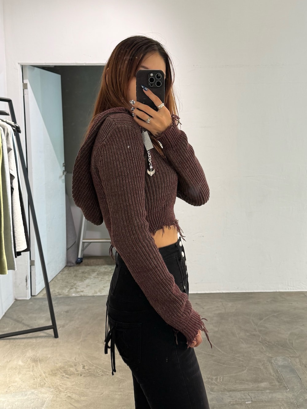 レッド系のニット/セーター、ブラック系のデニムパンツ、ブラック系のブーツを着用したレディースの冬コーディネートの5枚目の写真