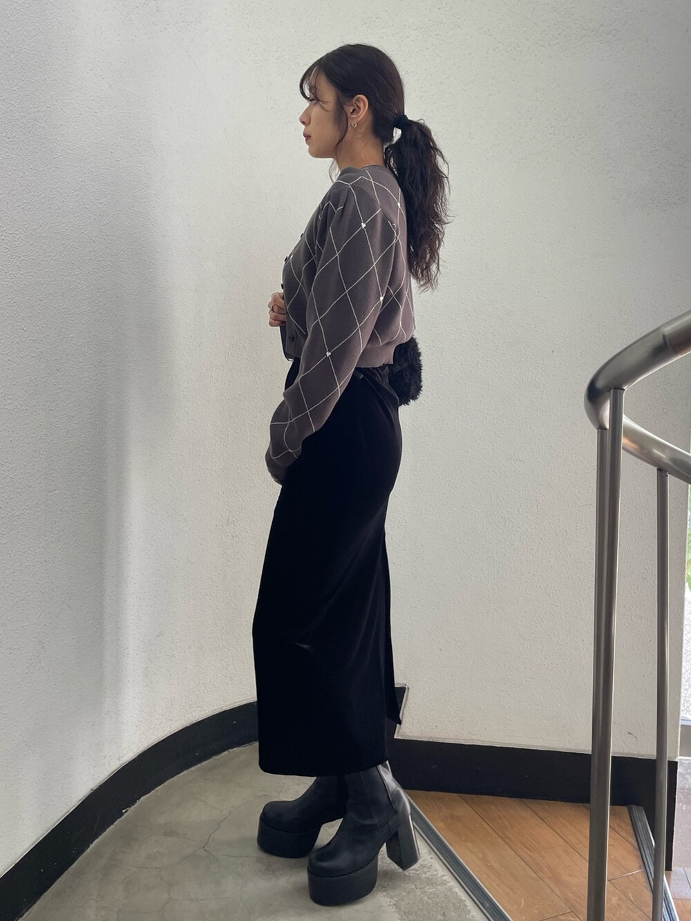 グレー系のニット/セーター、ブラック系のハンドバッグ、ブラック系のスカートを着用したレディースの秋コーディネートの2枚目の写真