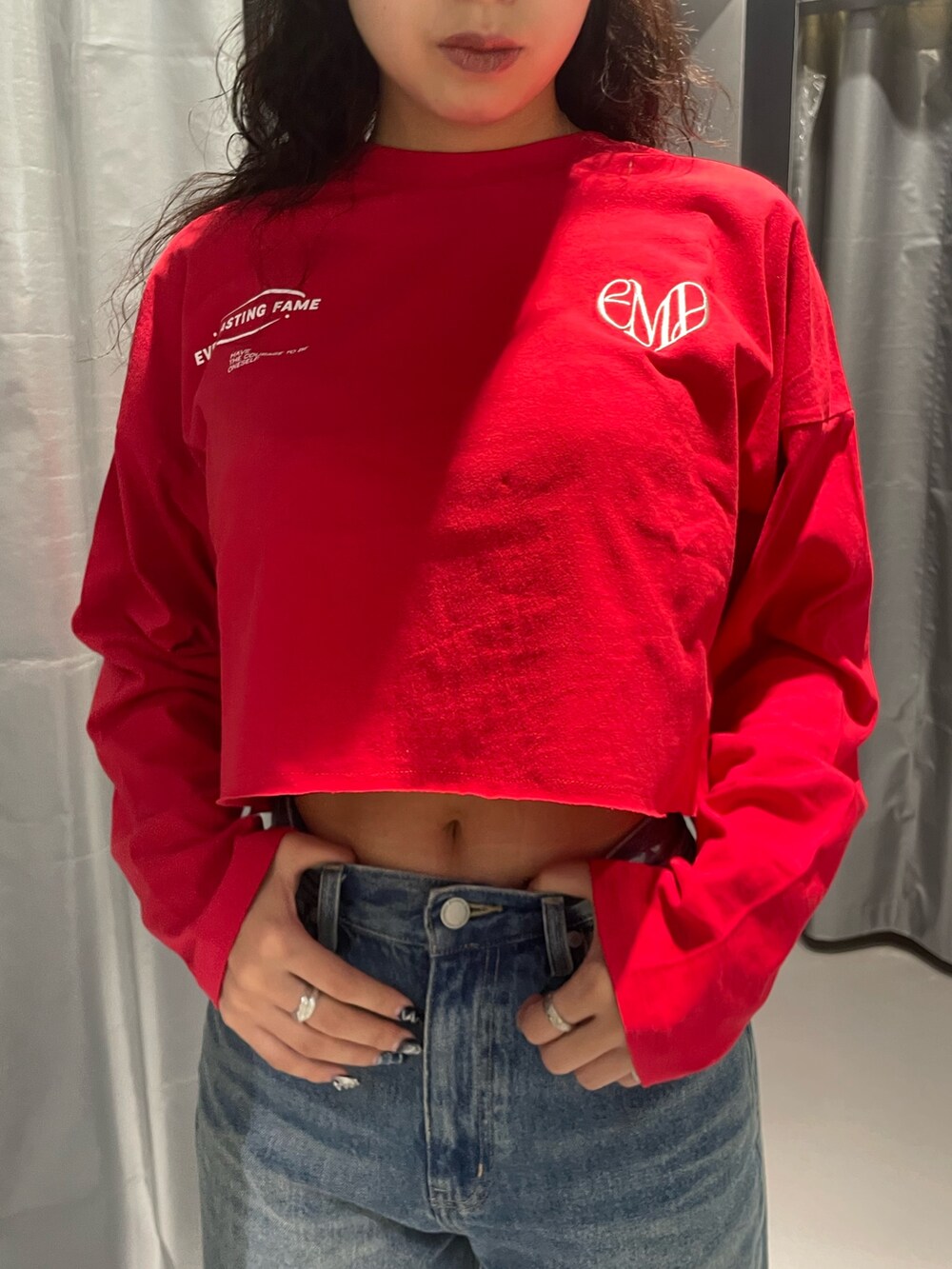 レッド系のTシャツ/カットソー、ブルー系のデニムパンツ、ブラック系のブーツを着用したレディースの秋コーディネートの4枚目の写真