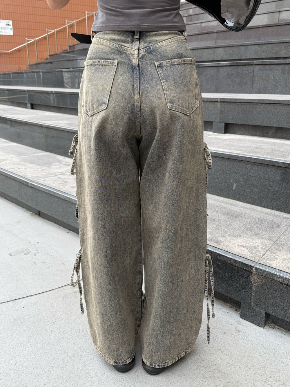 ブラック系のニット/セーター、ブルー系のデニムパンツ、ブラック系のサンダルを着用したレディースの夏コーディネートの9枚目の写真