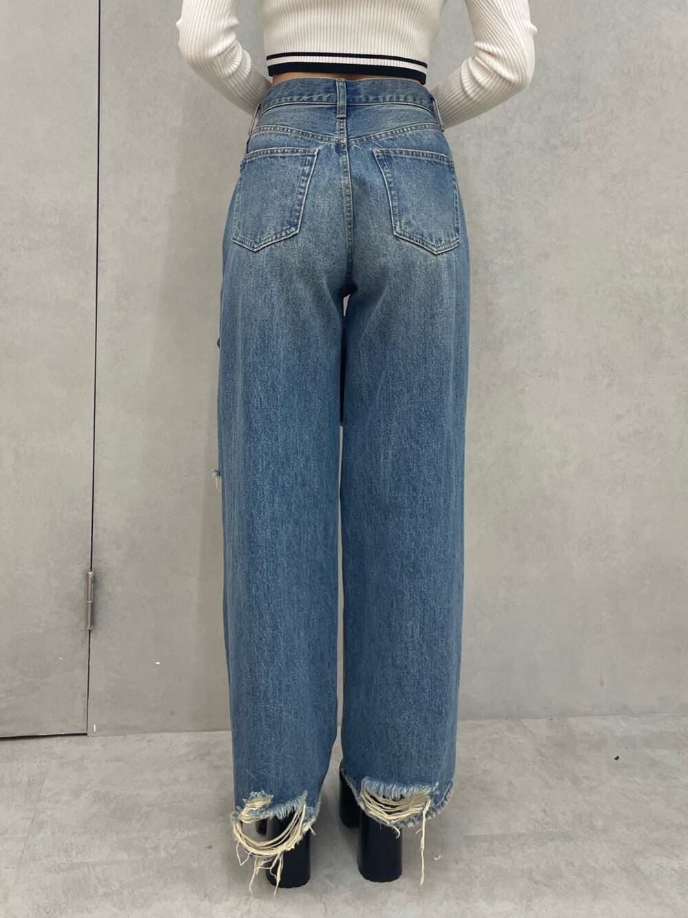 レッド系のTシャツ/カットソー、ブルー系のデニムパンツ、ブラック系のブーツを着用したレディースの秋コーディネートの8枚目の写真