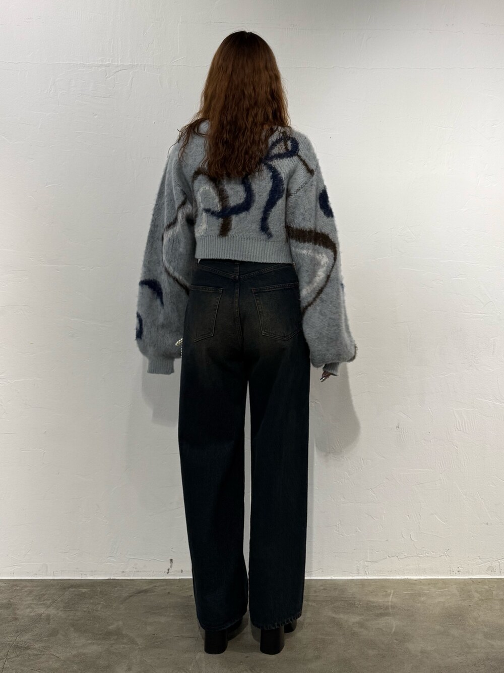 グレー系のニット/セーター、ブルー系のデニムパンツ、ブラック系のブーツを着用したレディースの秋コーディネートの3枚目の写真