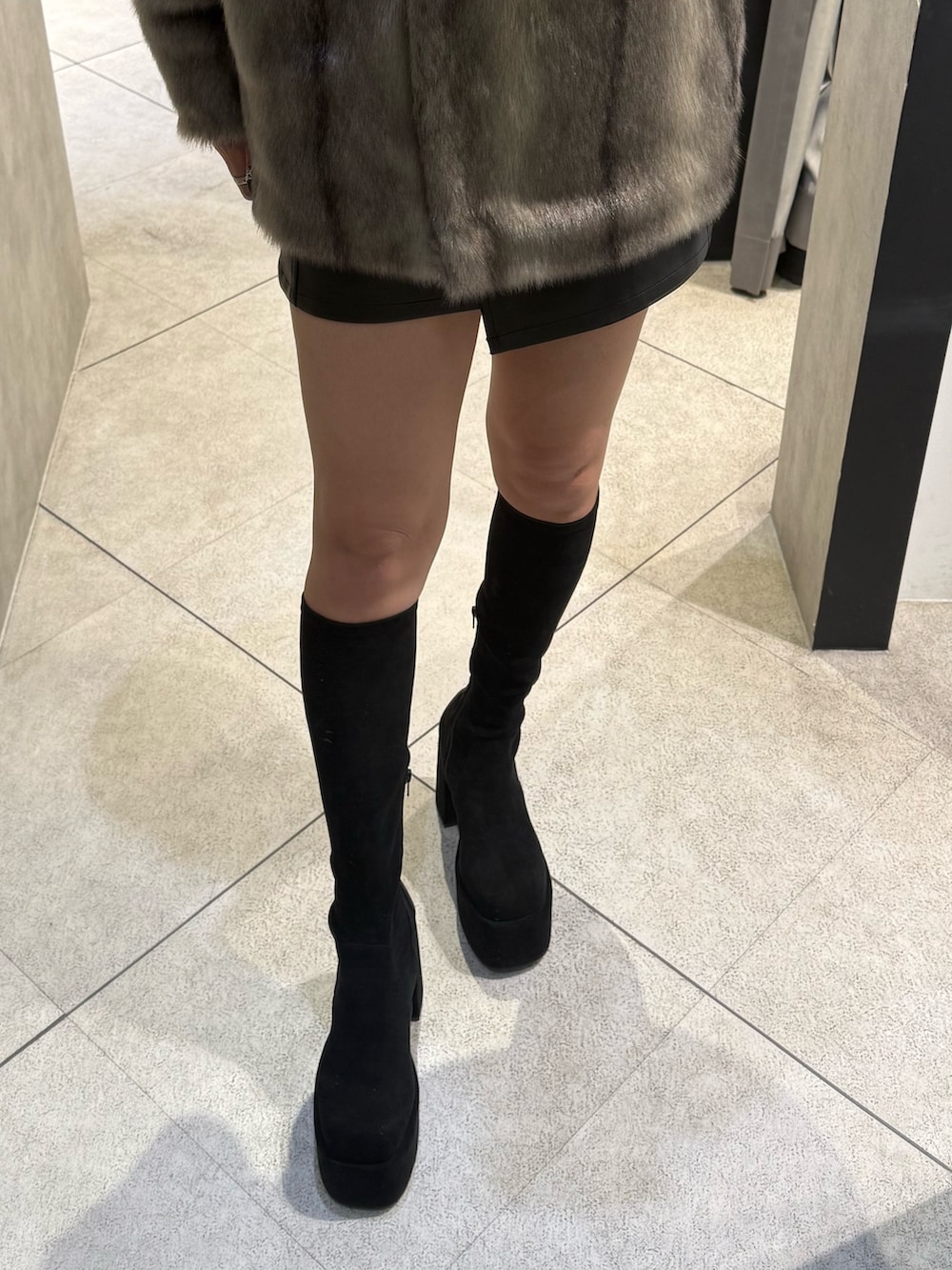 グレー系のその他アウター、ブラック系のスカート、ブラック系のブーツを着用したレディースの秋コーディネートの6枚目の写真