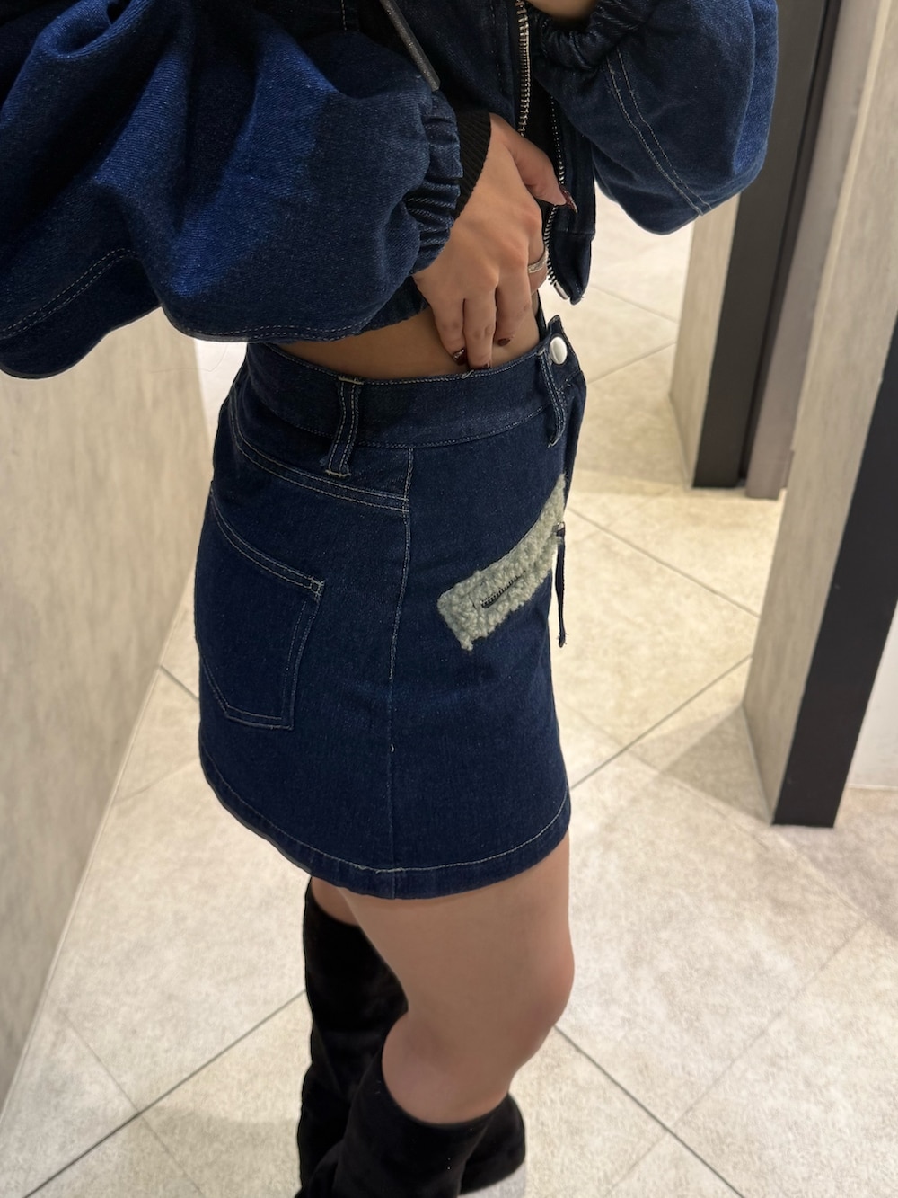 グレー系のニット/セーター、ブルー系のスカート、ブラック系のブーツを着用したレディースの秋コーディネートの6枚目の写真