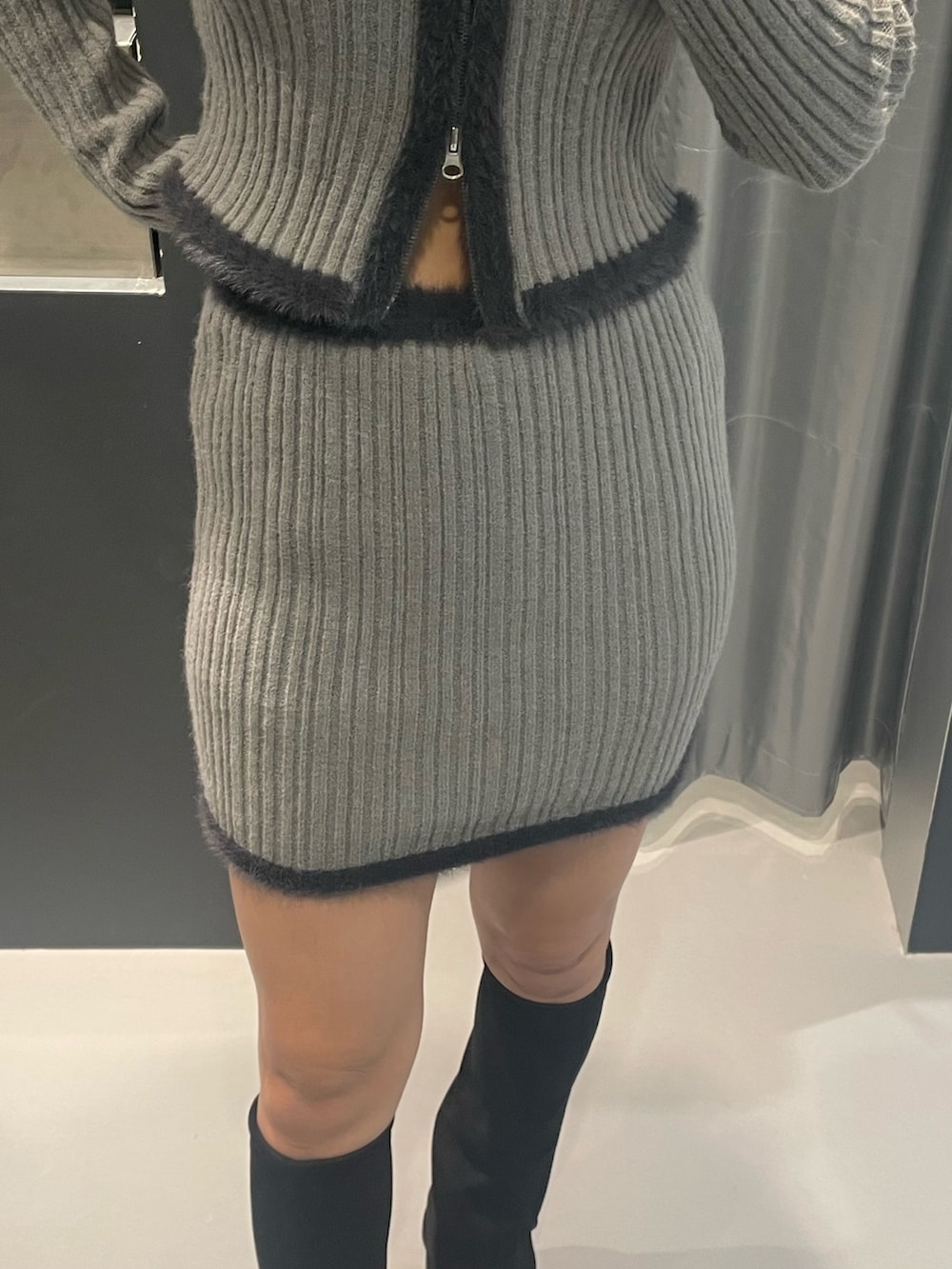 グレー系のニット/セーター、グレー系のスカート、ブラック系のブーツを着用したレディースの秋コーディネートの6枚目の写真