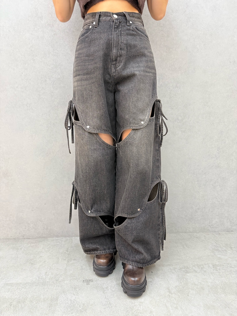 ブラウン系のニット/セーター、ブラック系のデニムパンツ、ブラウン系のブーツを着用したレディースの夏コーディネートの5枚目の写真